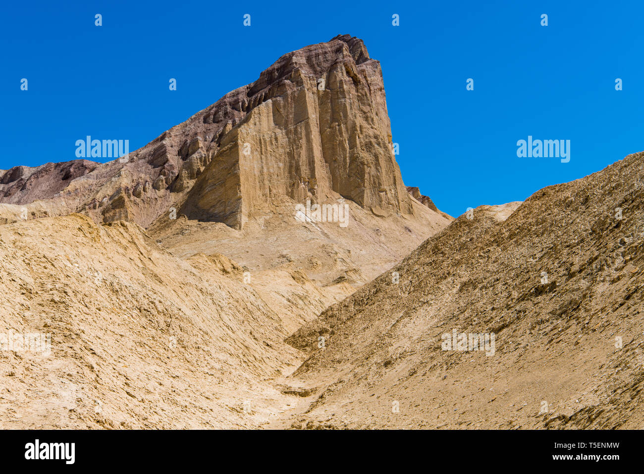 Un high desert en crête avec des falaises abruptes se dresse au-dessus d'un paysage de désert aride, golden - Golden Canyon dans Death Valley National Park Banque D'Images