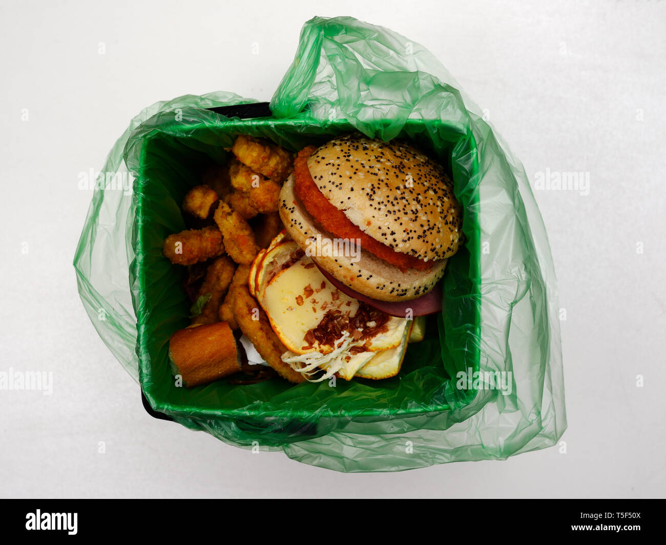 Déchets de restauration rapide dans un sac à déchets biodégradables sur fond blanc Banque D'Images