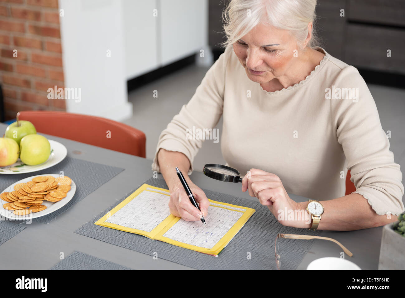 Senior woman jouit de la résolution d'un jeu de mots croisés à la maison Banque D'Images