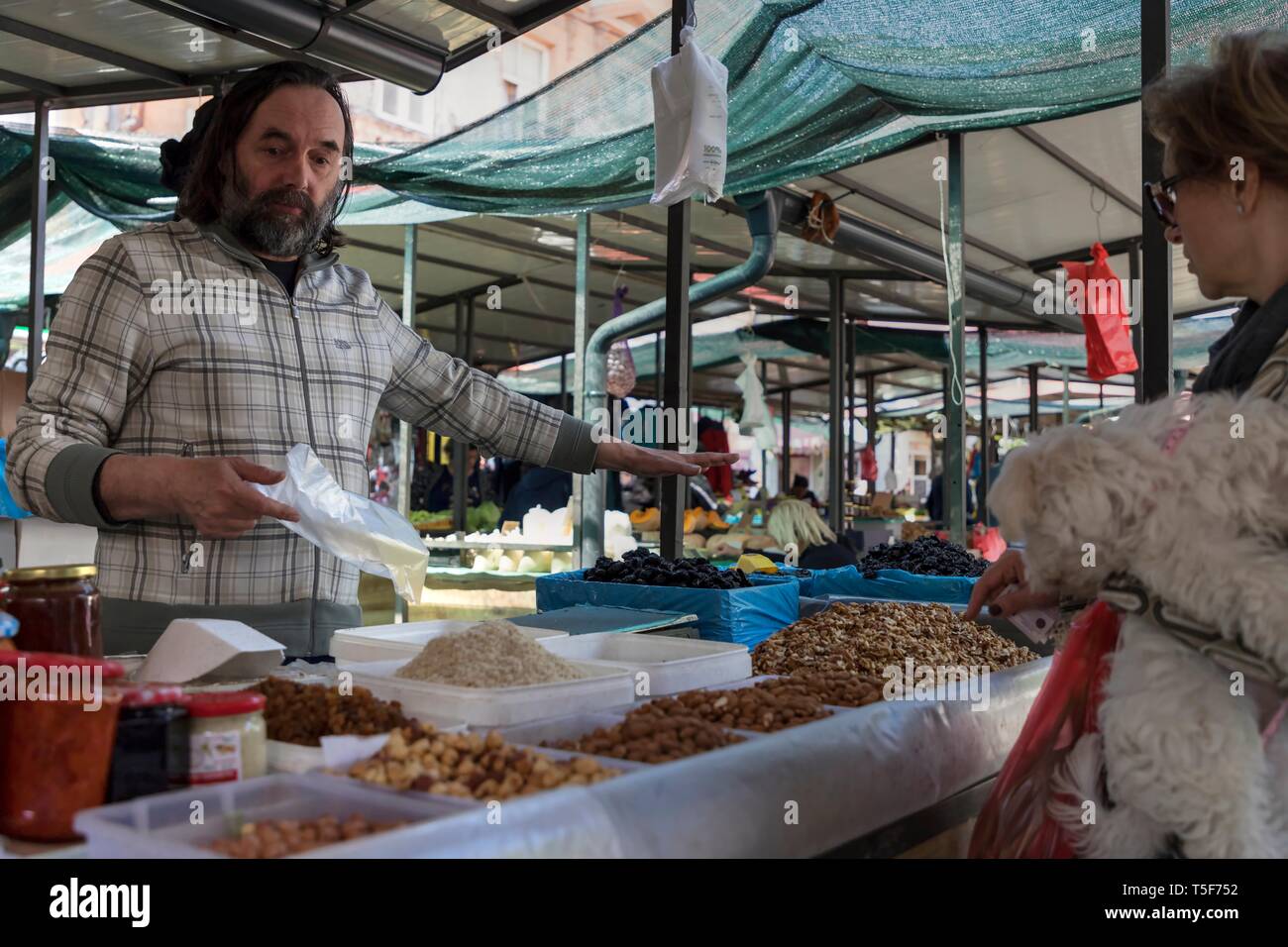 Zemun, Serbie, 19 avril 2019 : marché vert scène avec vendeur vente de noix & fruits séchés et lady tenant dans ses bras un petit chien Banque D'Images