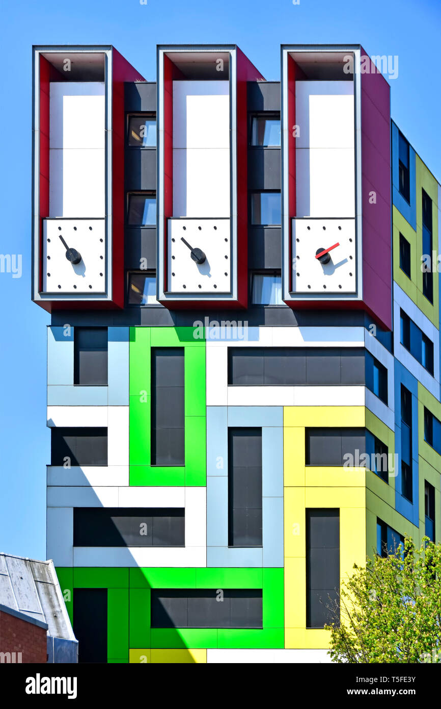 Aiguilles d'horloge sur la tour de l'horloge haute inhabituelle sur le dessus de l'architecture moderne coloré construit logements étudiants appartements color motif géométrique UK Banque D'Images