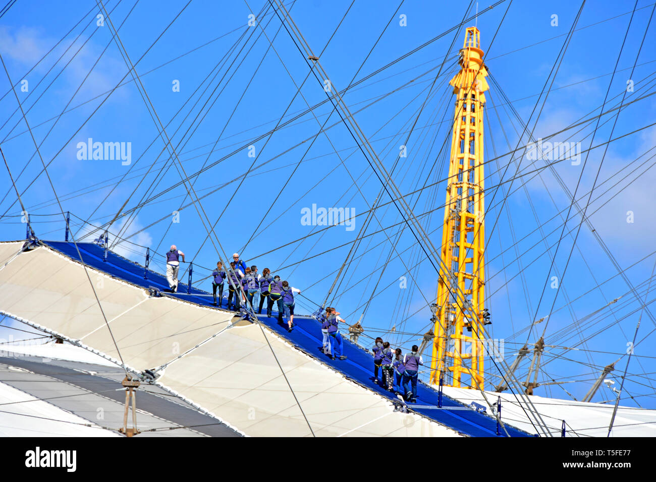 Jusqu'à l'O2 Arena de toit dôme du millénaire et toit Skywalk à pied groupe de personnes porter des blouses bleus d'escalade haut de O2 arena tour leader guide UK Banque D'Images