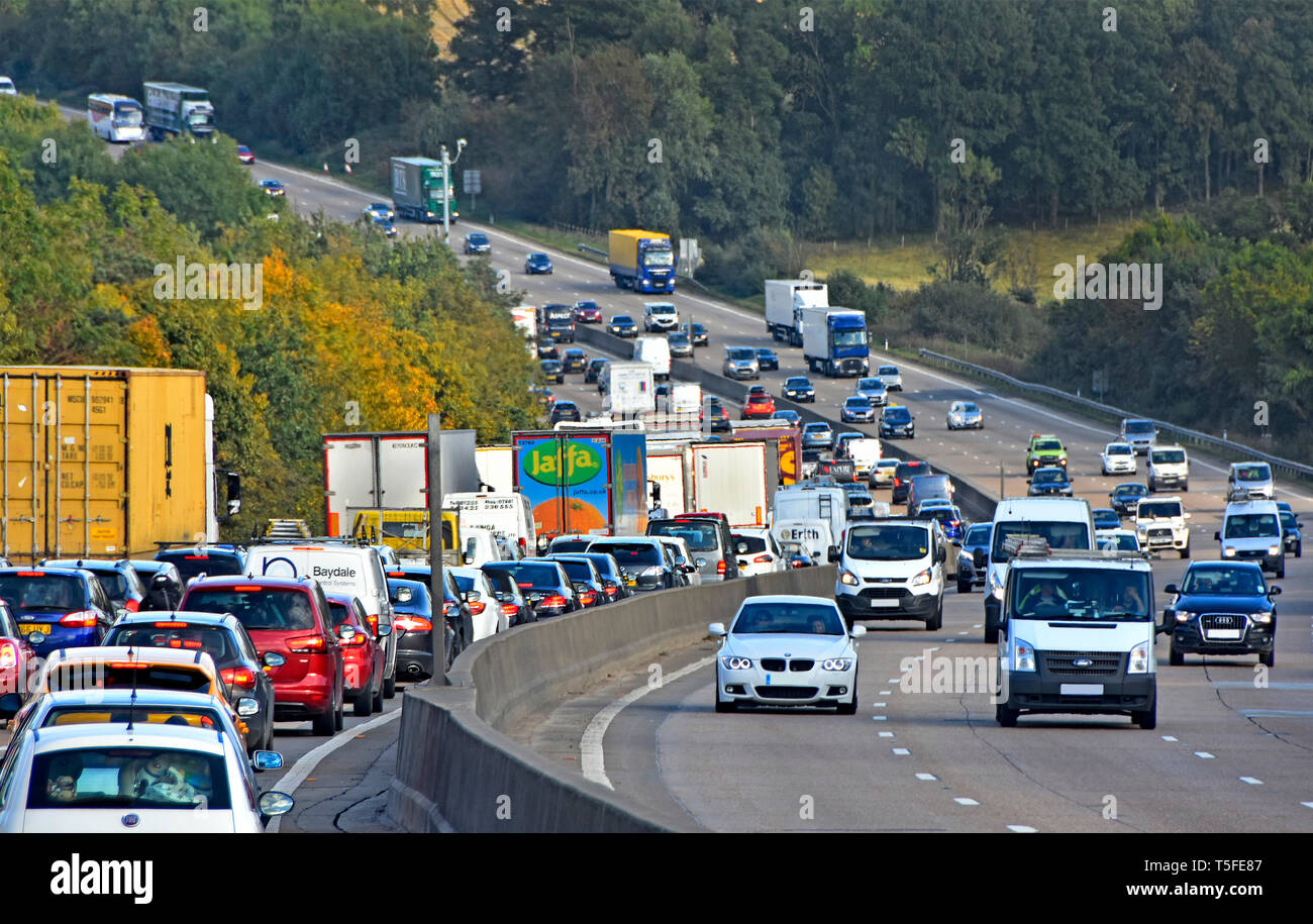 L'heure de pointe sur l'autoroute BRITANNIQUE M25 queue de voitures, camions et camions en circulation dans une campagne vallonnée de Londres Angleterre Royaume-uni autoroute orbitale Banque D'Images