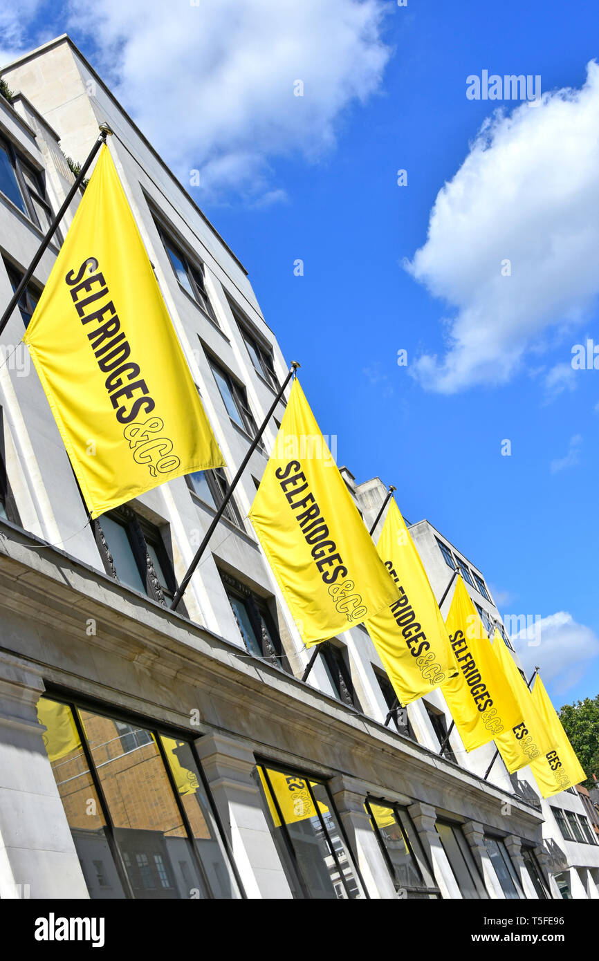 Grand magasin Selfridges à l'aide de bannière jaune pour annoncer l'image de marque et faire de même sur une ligne longue de bannières identiques pour l'impact West End de Londres UK Banque D'Images