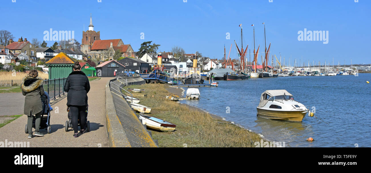 Les mamans et la pram marche-Promenade Riverside hiver panorama du parc à côté de l'estuaire de la rivière Blackwater à marée haute tamise les chalands au-delà de Maldon Essex England UK Banque D'Images