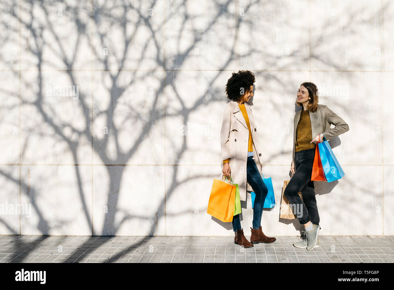 Deux femmes heureux de parler à un mur permanent Banque D'Images