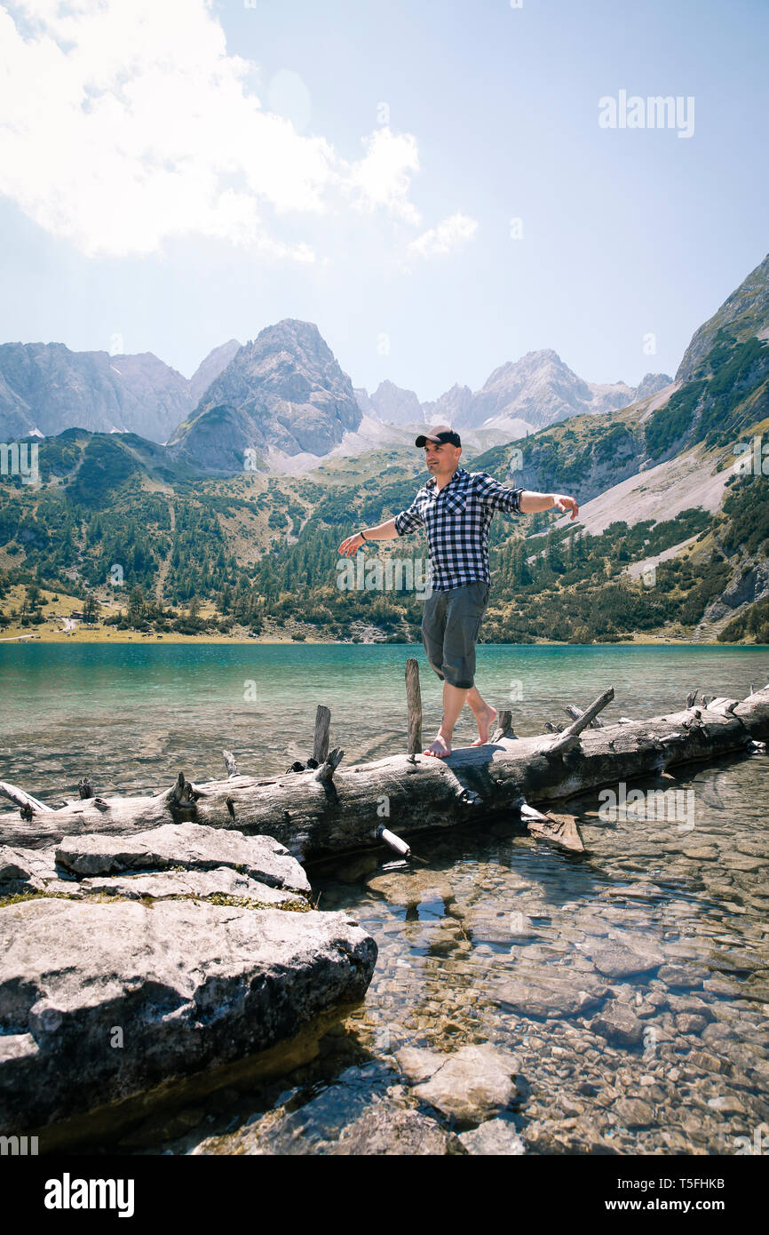 L'Autriche, le Tyrol, l'homme en équilibre sur tronc d'arbre au lac Seebensee Banque D'Images