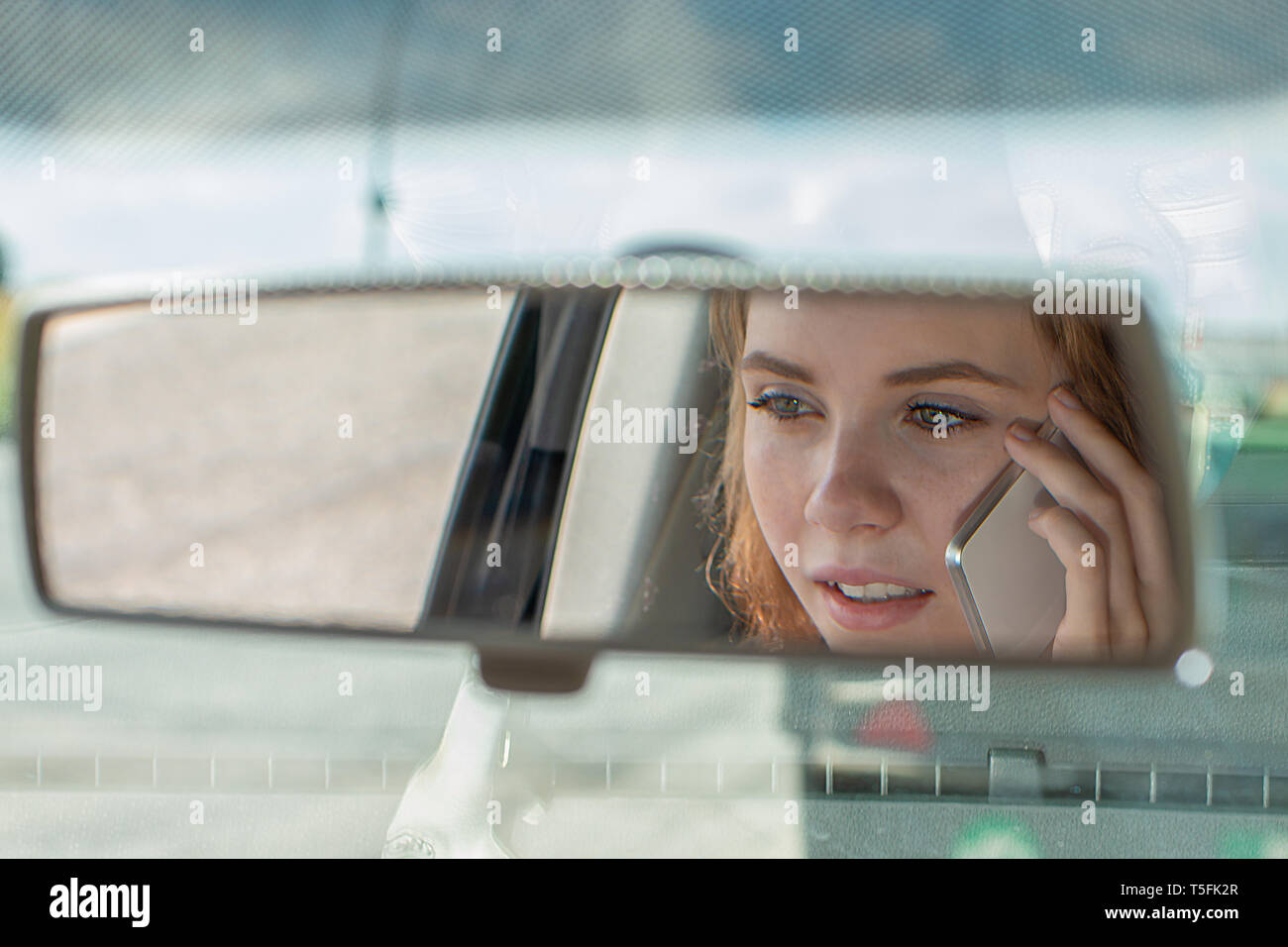 Jeune femme conduit sa voiture et parle sur le téléphone mobile Banque D'Images