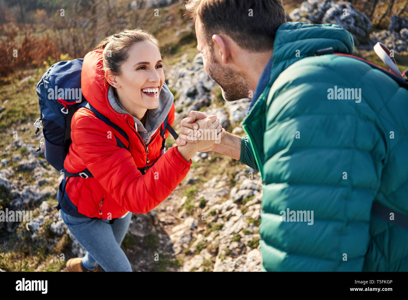Man helping girlfriend climbing rock en randonnée dans les montagnes Banque D'Images