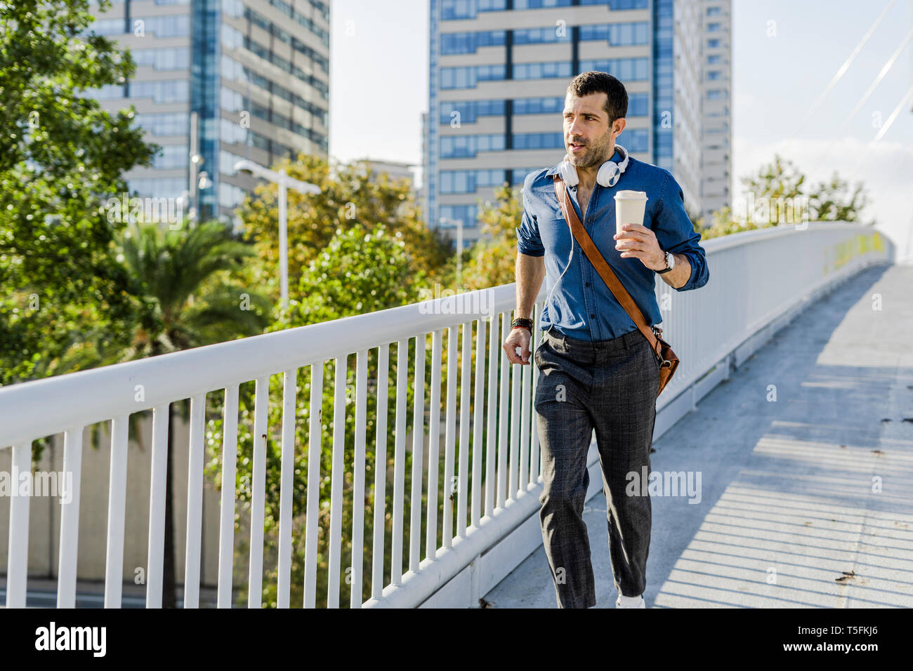 Portrait d'homme avec du café pour aller courir sur un pont Banque D'Images