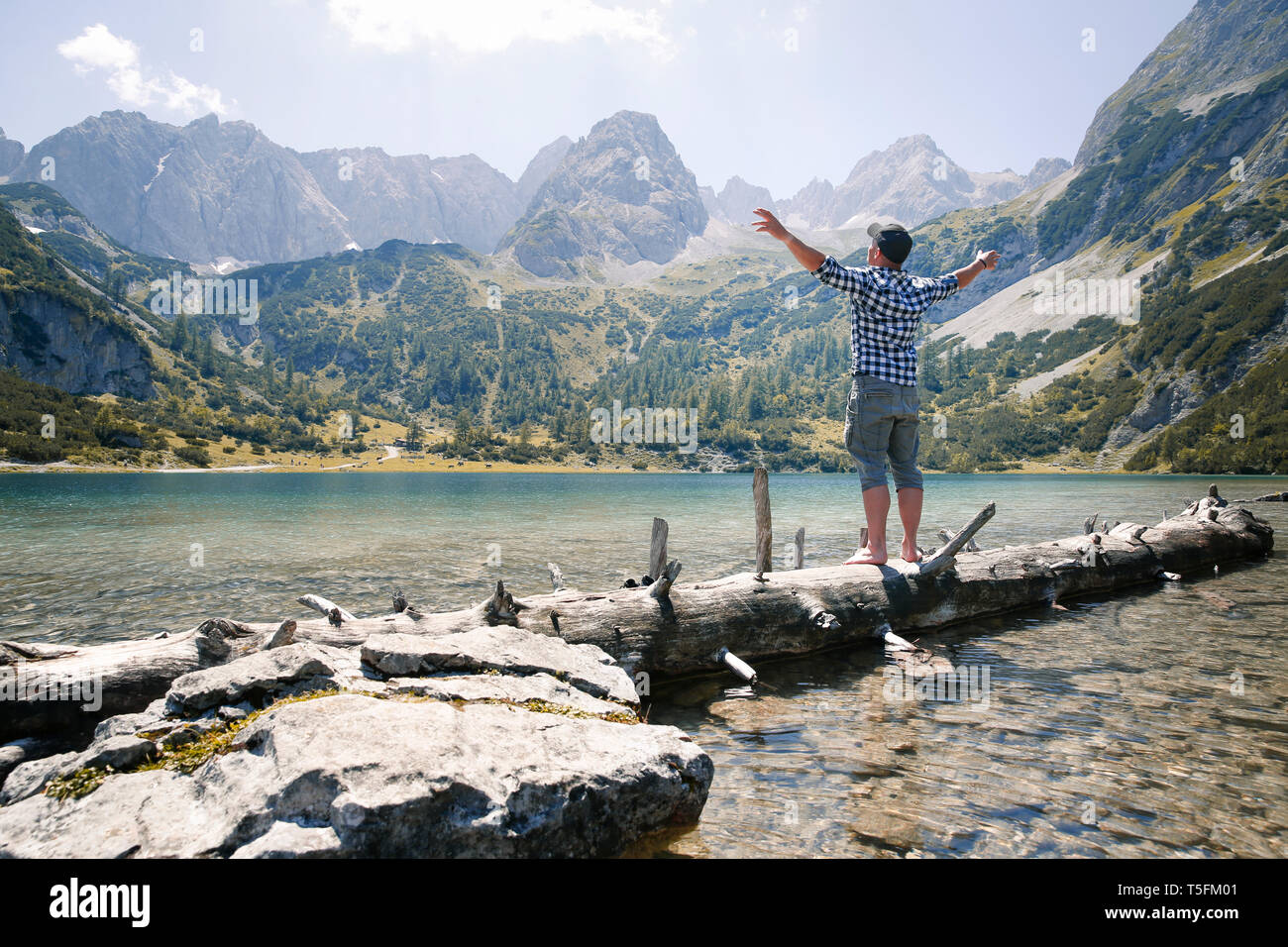 L'Autriche, le Tyrol, l'homme debout sur le tronc de l'arbre au lac Seebensee Banque D'Images