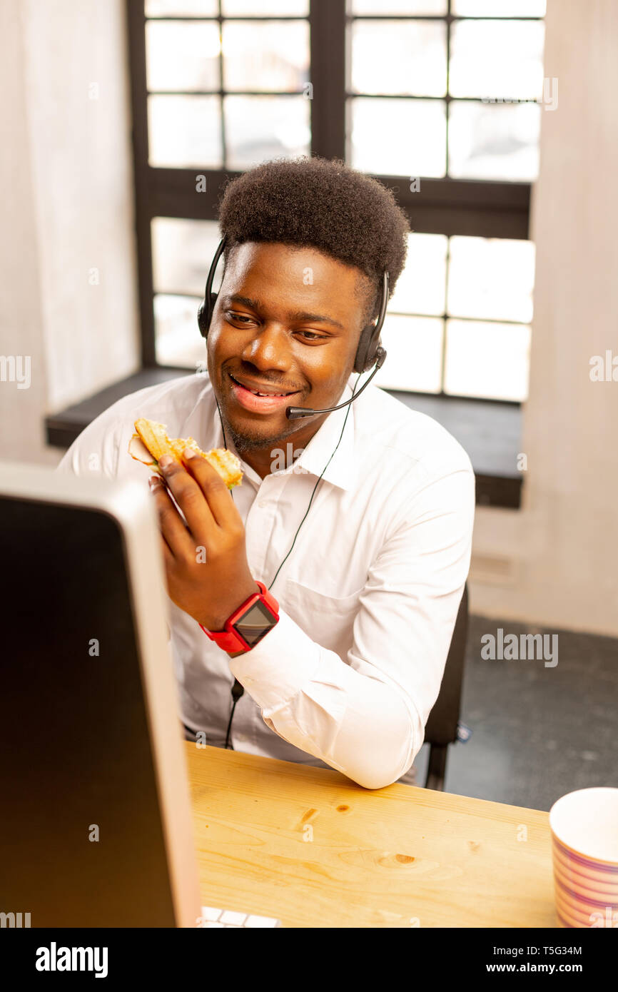 Nice positif homme assis avec un sandwich Banque D'Images