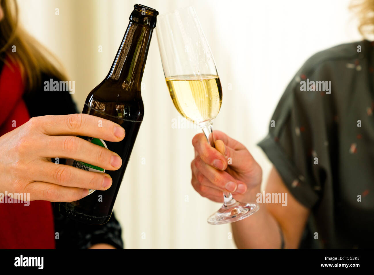 Vue détaillée de deux femmes faire un toast avec une bouteille de bière et un verre de champagne Banque D'Images