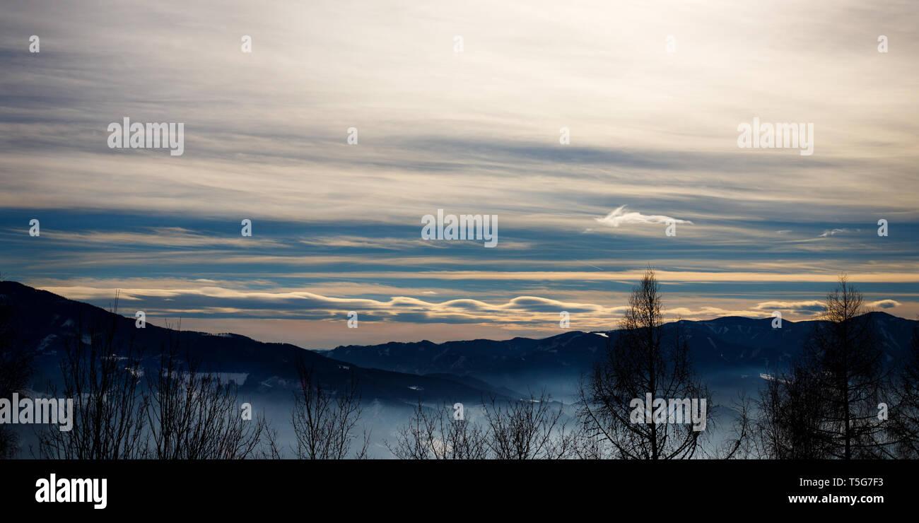 Avec un panorama d'hiver Alpin misty valley avec les nuages et les montagnes brumeuses du ciel d'hiver dans les Alpes européennes Banque D'Images