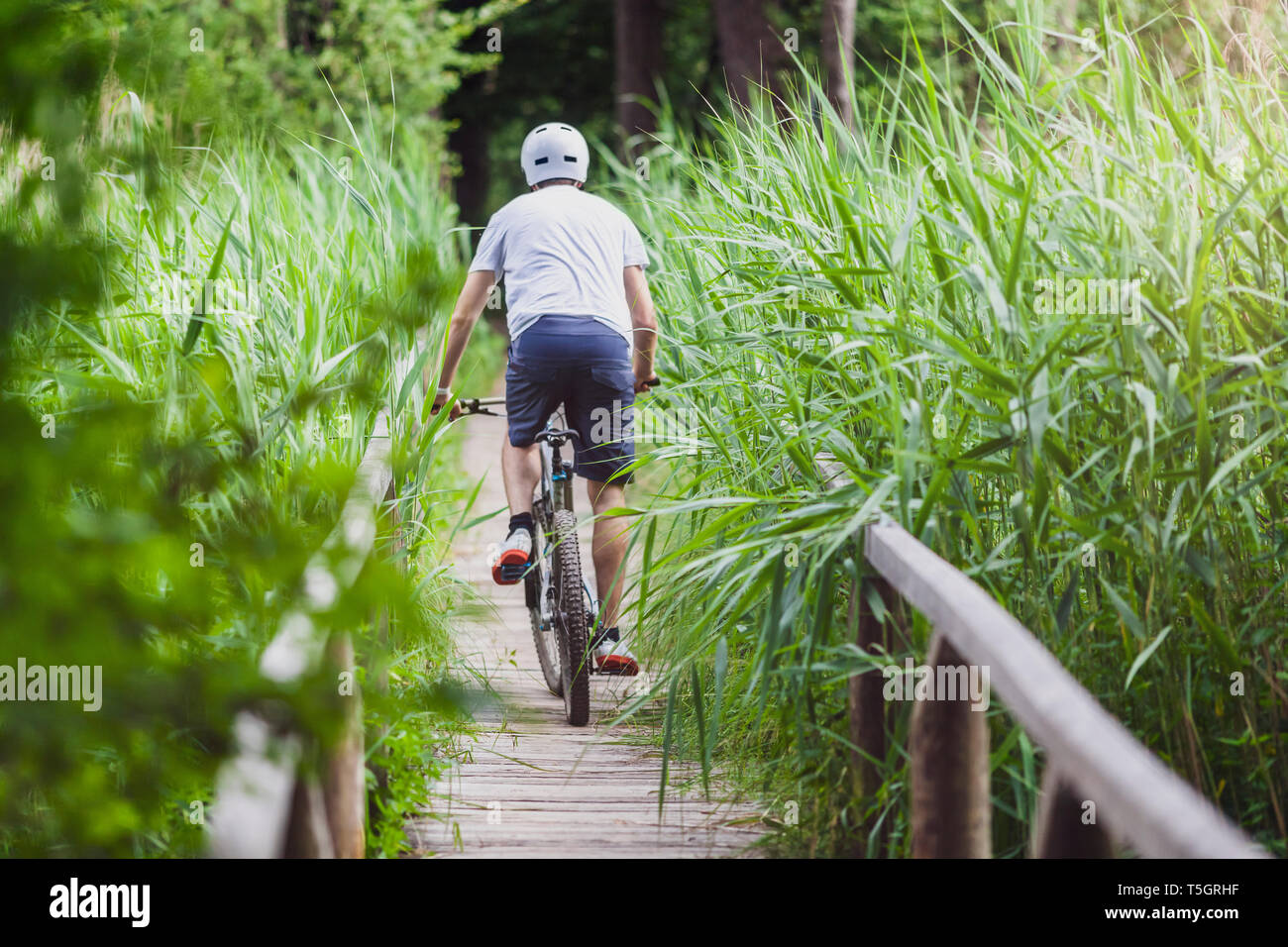 Man on mountain bike de traverser un pont sur un lac Banque D'Images