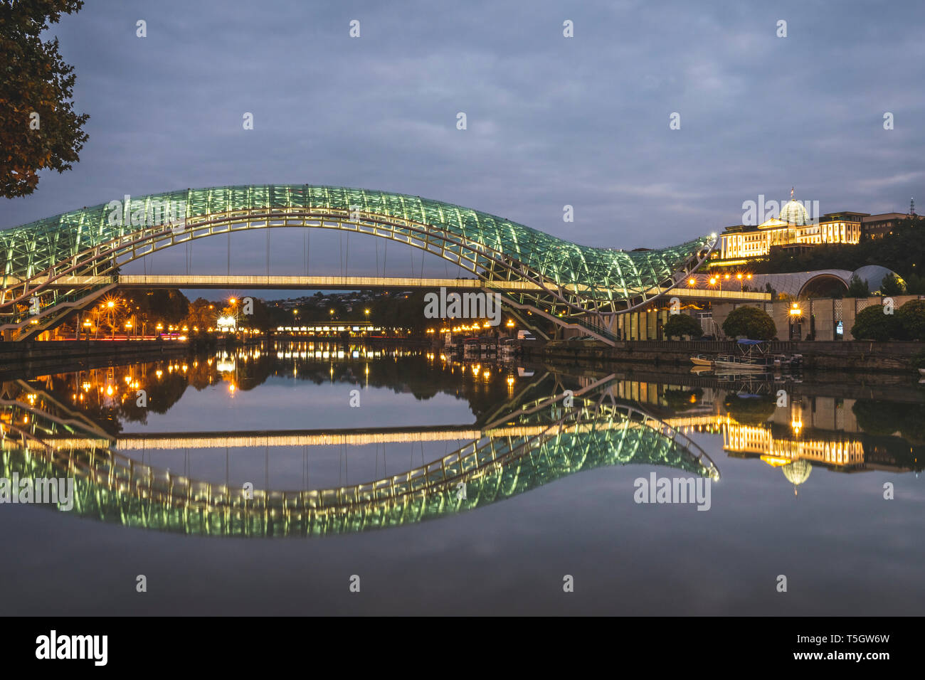 La Géorgie, Tbilissi, pont de la paix sur la rivière Kura dans la nuit avec le parlement en arrière-plan Banque D'Images