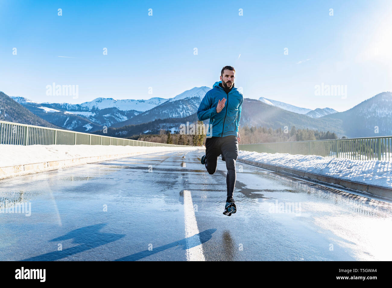 Germany, Bavaria, sportif homme qui court sur une route en hiver Banque D'Images