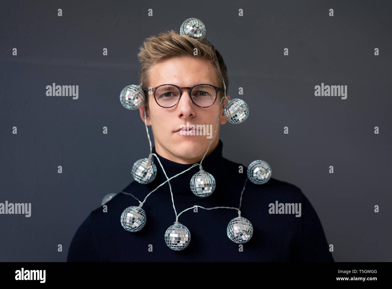 Portrait of young man wearing mirror ball fairy lights Banque D'Images