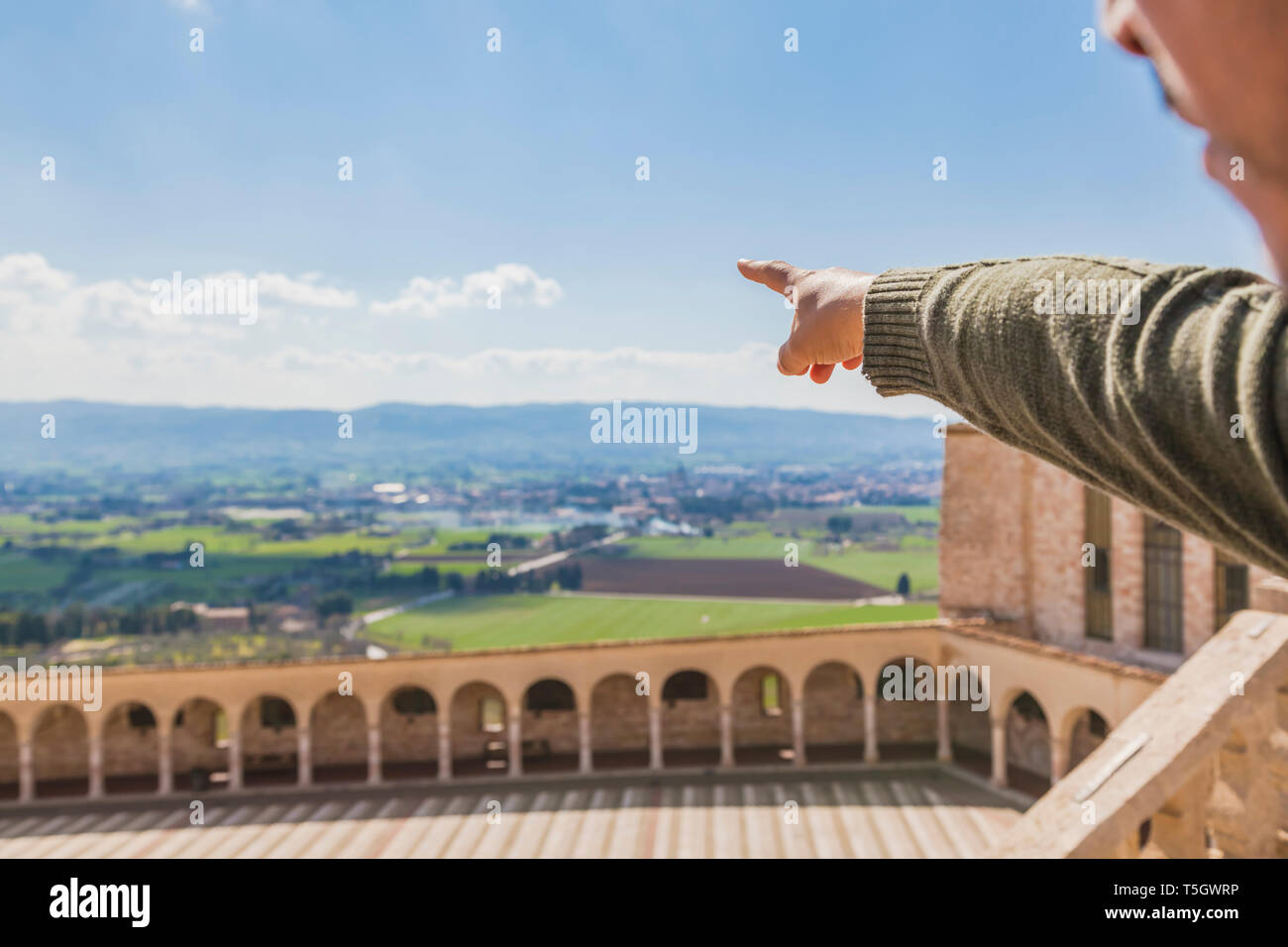 L'Italie, l'Ombrie, assise, la main de l'homme pointant sur les champs entourant la basilique de San Francesco d'Assisi Banque D'Images