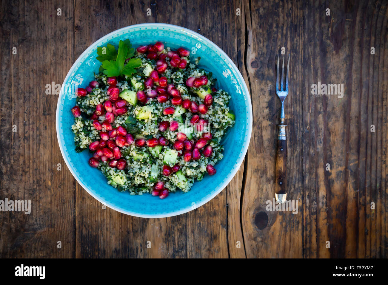 Bol de salade de boulgour au concombre, d'herbes, de graines de grenade et du persil Banque D'Images