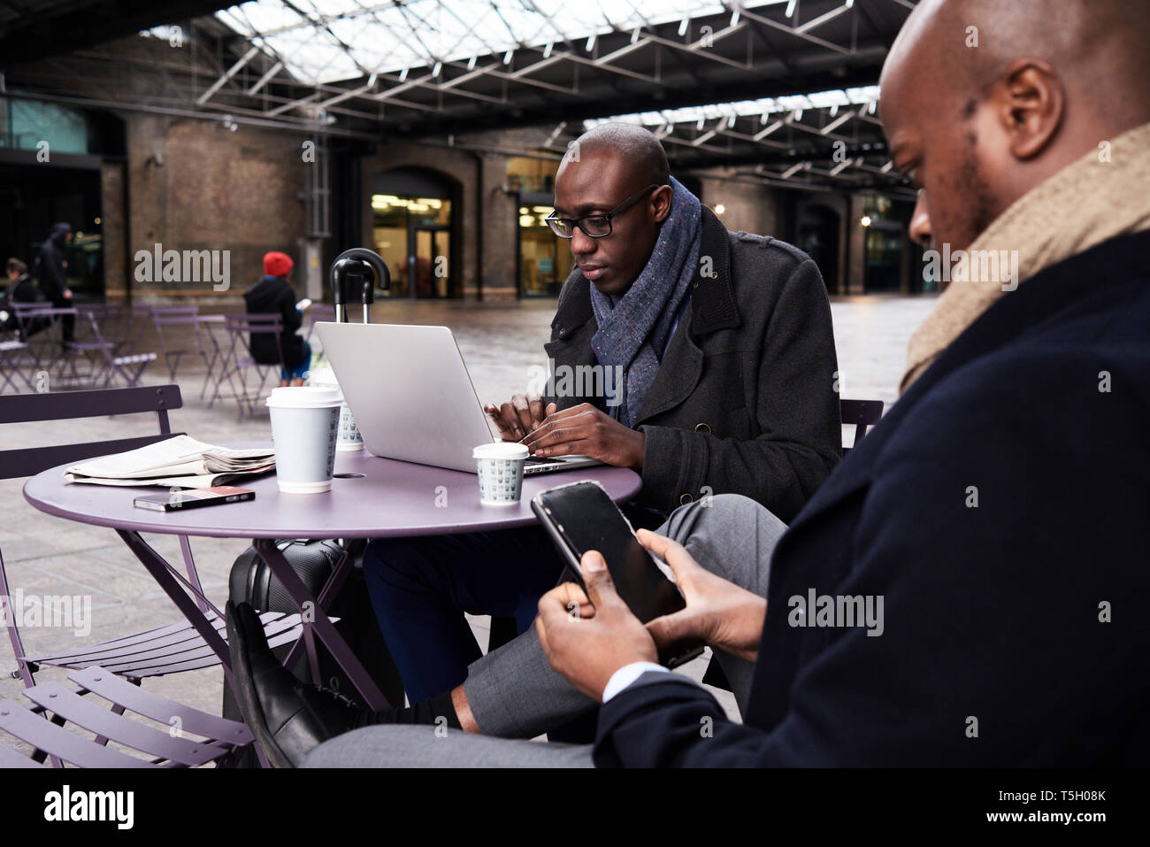 Deux hommes assis à table de café à l'aide d'appareils mobiles Banque D'Images