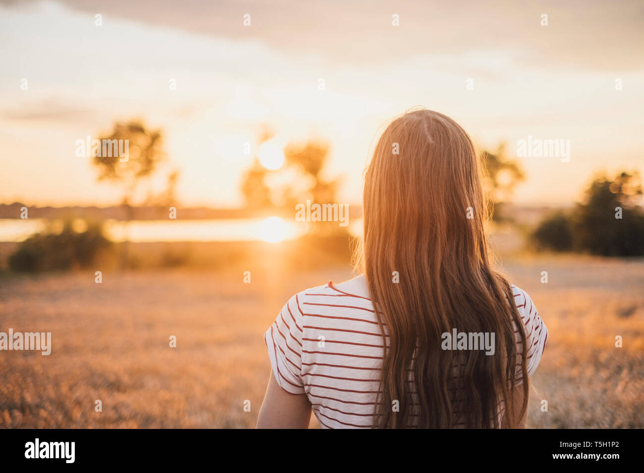 Vue arrière de jeune femme regardant le coucher du soleil Banque D'Images