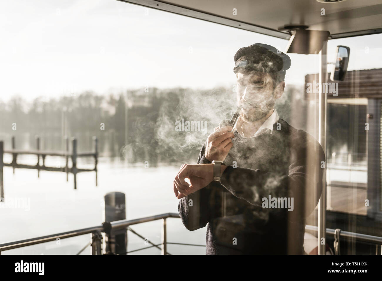 Homme avec un captain's hat debout sur un housebpat pipe, Banque D'Images