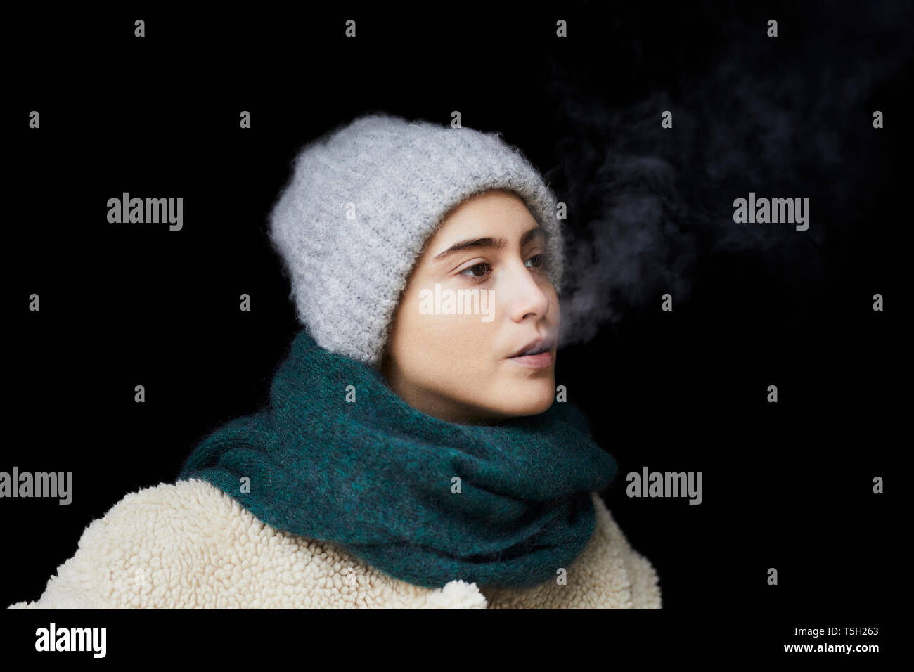Portrait de jeune femme dans des vêtements d'hiver fumeurs Banque D'Images