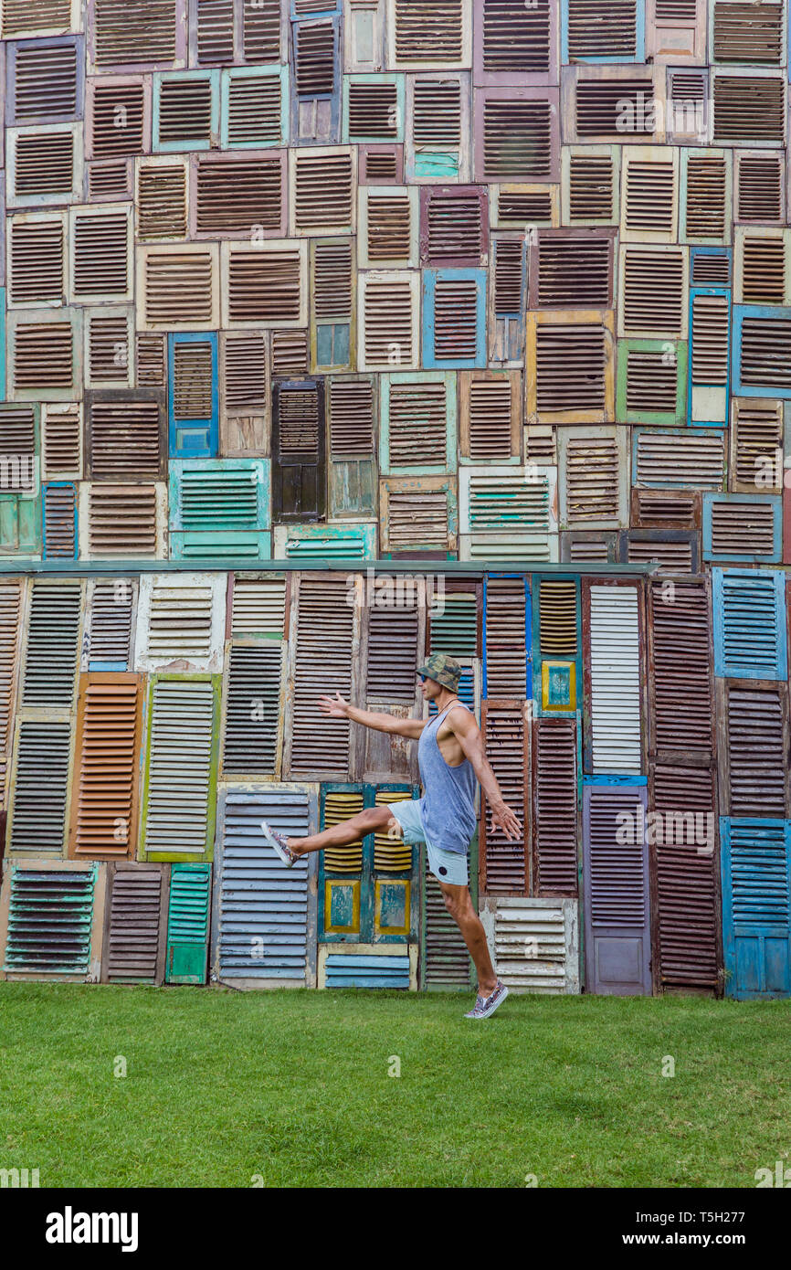 L'INDONÉSIE, Bali, l'homme marchant au mur de fenêtres en bois Banque D'Images
