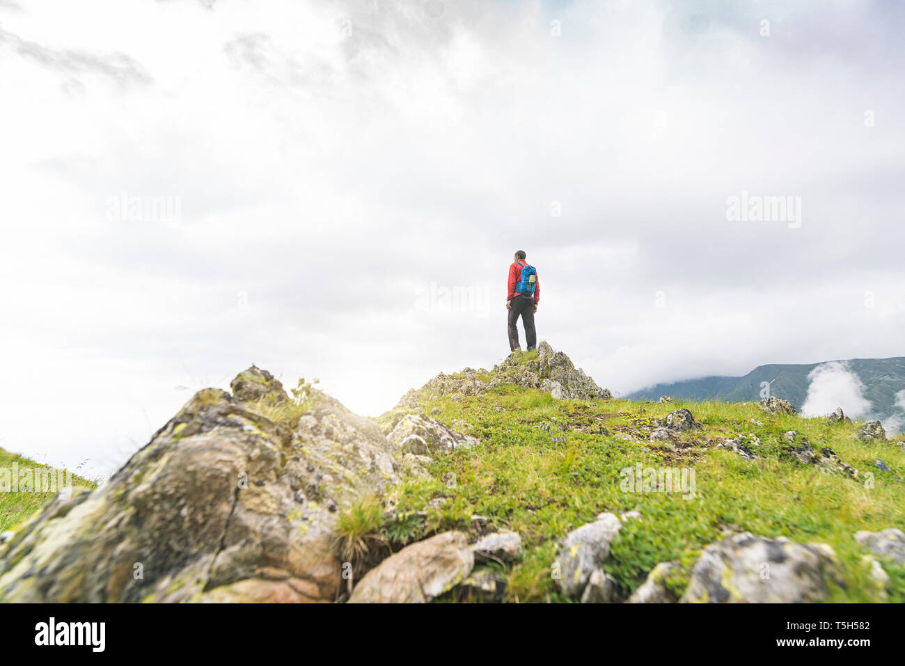 Homme debout au sommet d'une colline et en regardant le paysage dans les montagnes des Carpates, Roumanie Banque D'Images