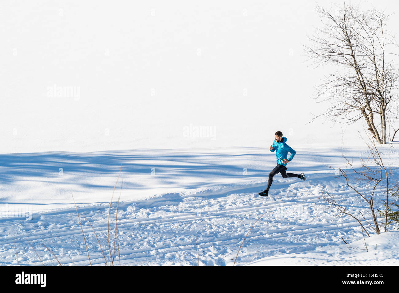 Germany, Bavaria, sportif homme qui court dans la neige en hiver Banque D'Images
