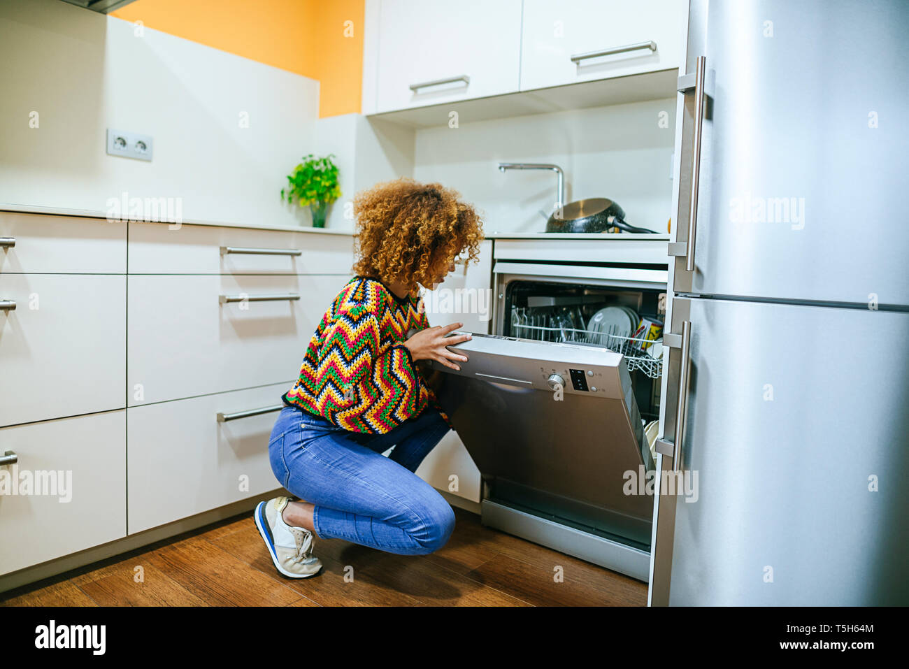 Jeune femme avec le lave-vaisselle à ouverture bouclés cuisine Banque D'Images