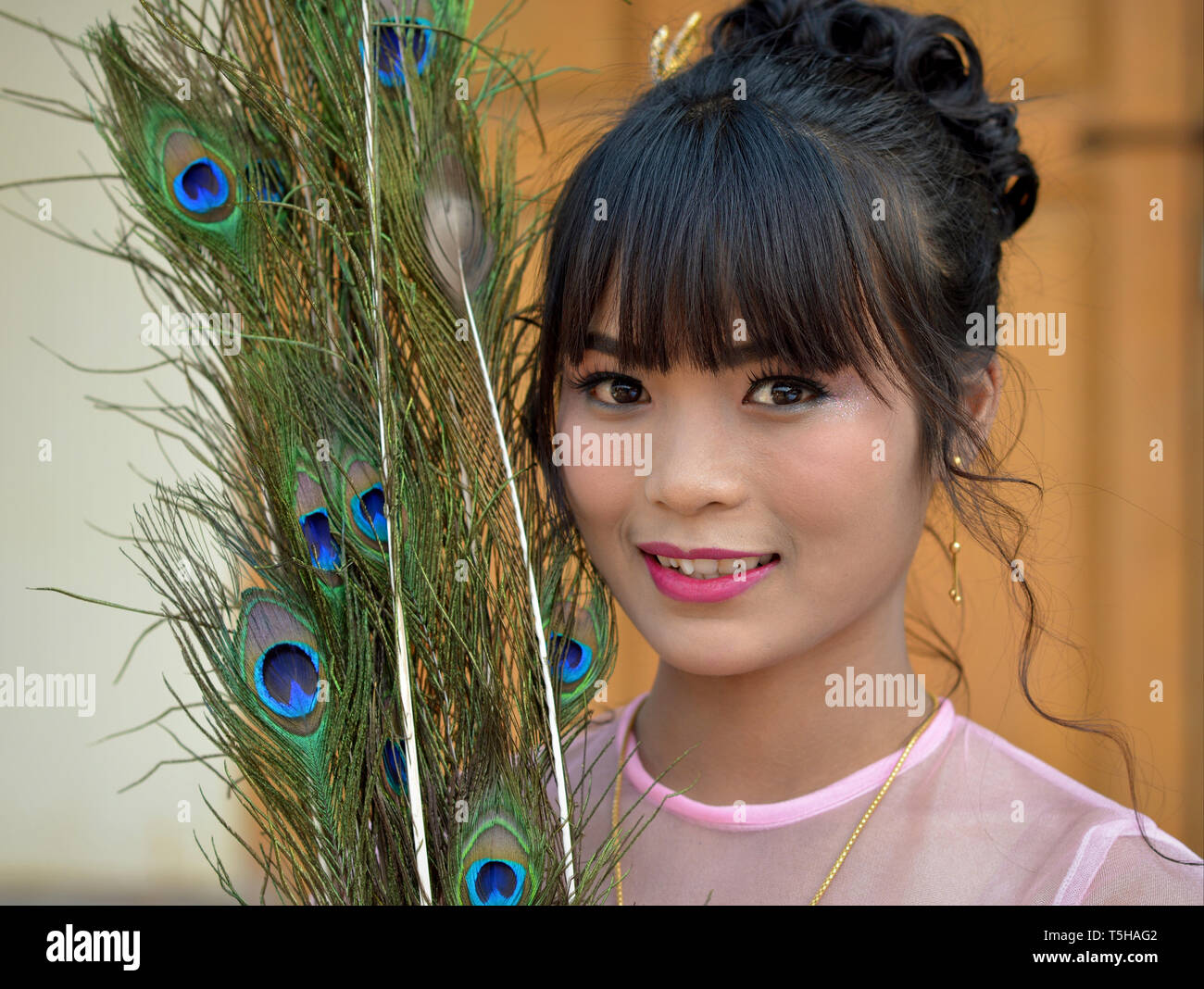 Belle jeune femme birmane avec plumes de paon pose pour la caméra. Banque D'Images