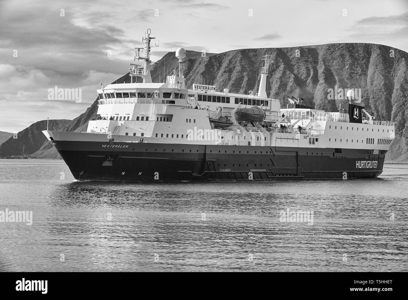 Photo en noir et blanc du navire Hurtigruten, MS Vesterålen approchant de la ville norvégienne de pêcheurs de Honningsvåg, au nord du cercle polaire arctique. Norvège. Banque D'Images