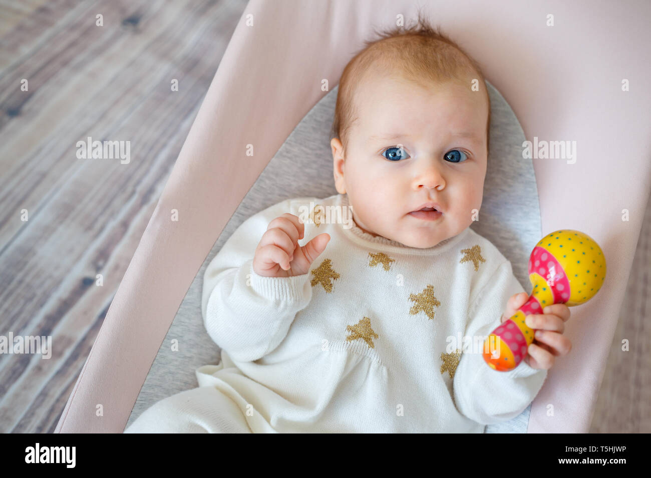 Adorable baby girl in videur. Toddler Playing with toy hochet coloré à l'intérieur. Activités pour enfants Banque D'Images