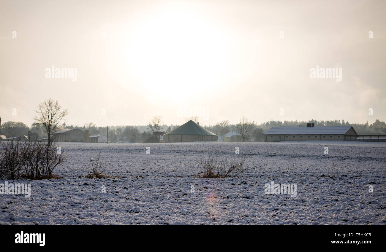 Un champ de neige gelée et un village de l'arrière-plan au milieu de nulle part par une froide journée ensoleillée en hiver Banque D'Images