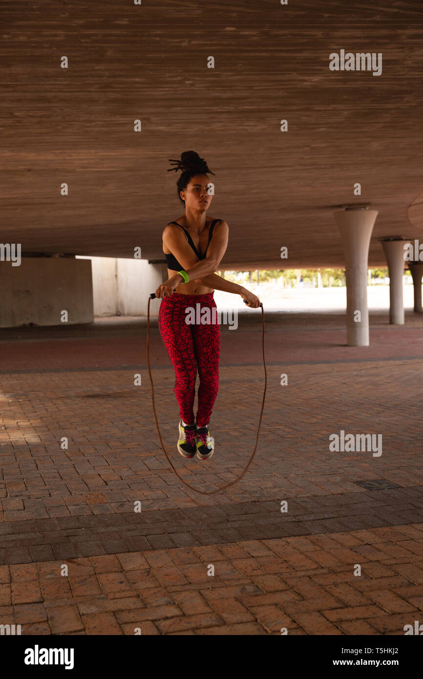 Young woman exercising with la corde à sauter sous un pont Banque D'Images Young woman exercising with la corde à sauter sous un pont Banque D'Images