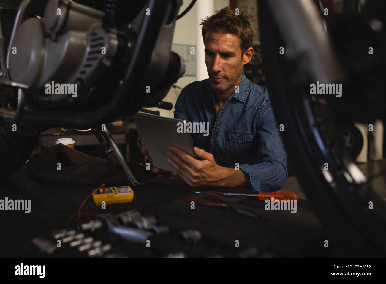 Mécanicien vélo à l'aide de tablette numérique tout en travaillant dans un garage Banque D'Images