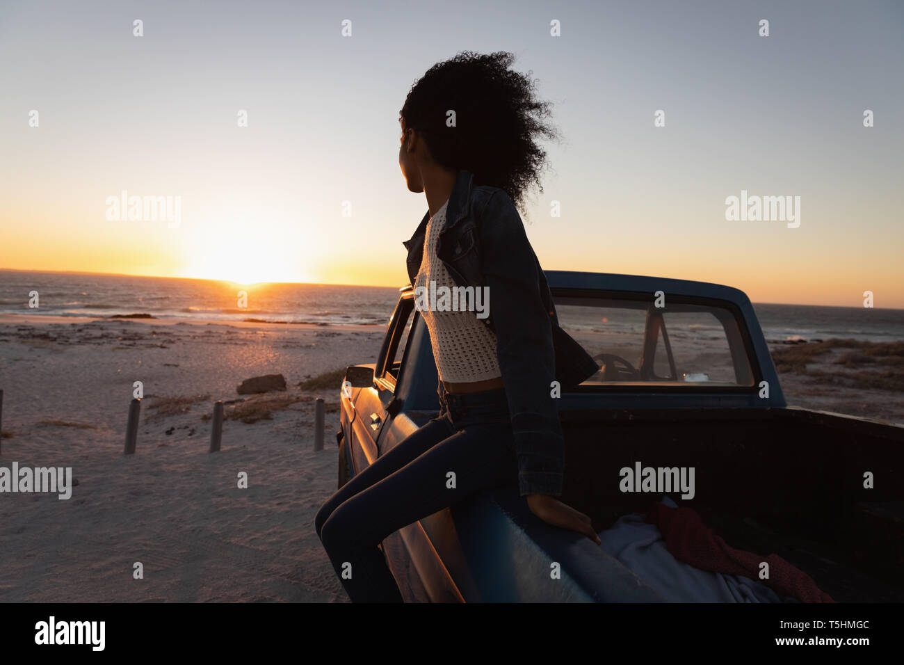 Belle femme assise dans une voiture sur la plage Banque D'Images