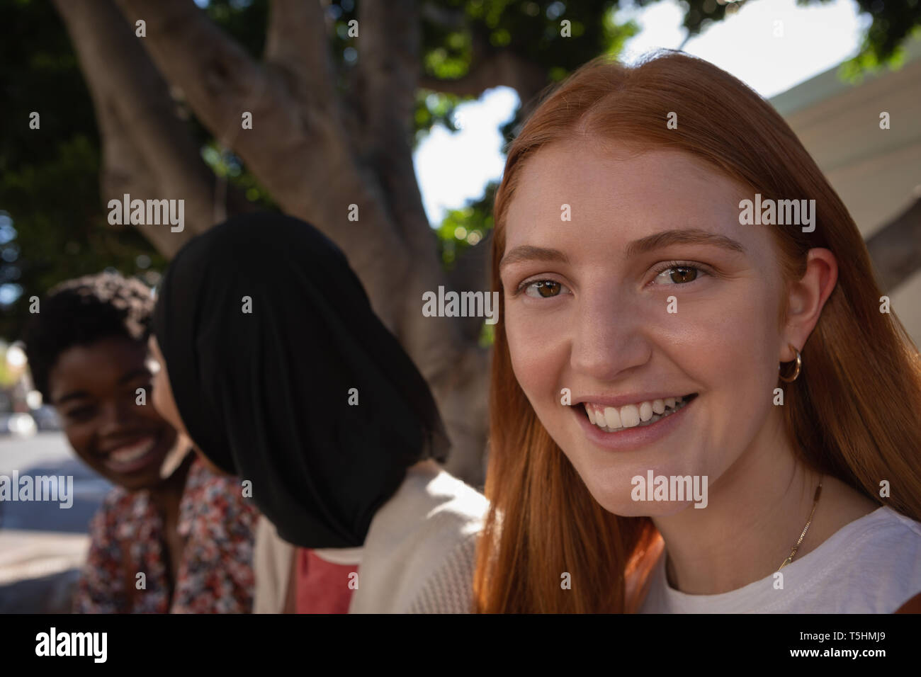 Belle femme assise sous l'arbre tandis que les amis talking on background Banque D'Images Belle femme assise sous l'arbre tandis que les amis talking on background Banque D'Images