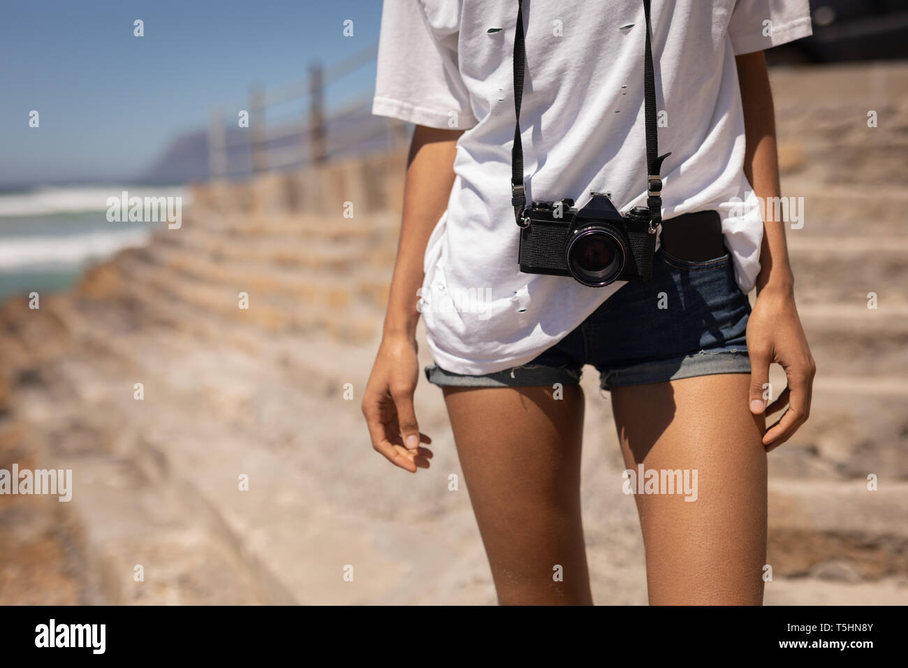Femme debout avec l'appareil photo à la plage sur une journée ensoleillée Banque D'Images Femme debout avec l'appareil photo à la plage sur une journée ensoleillée Banque D'Images