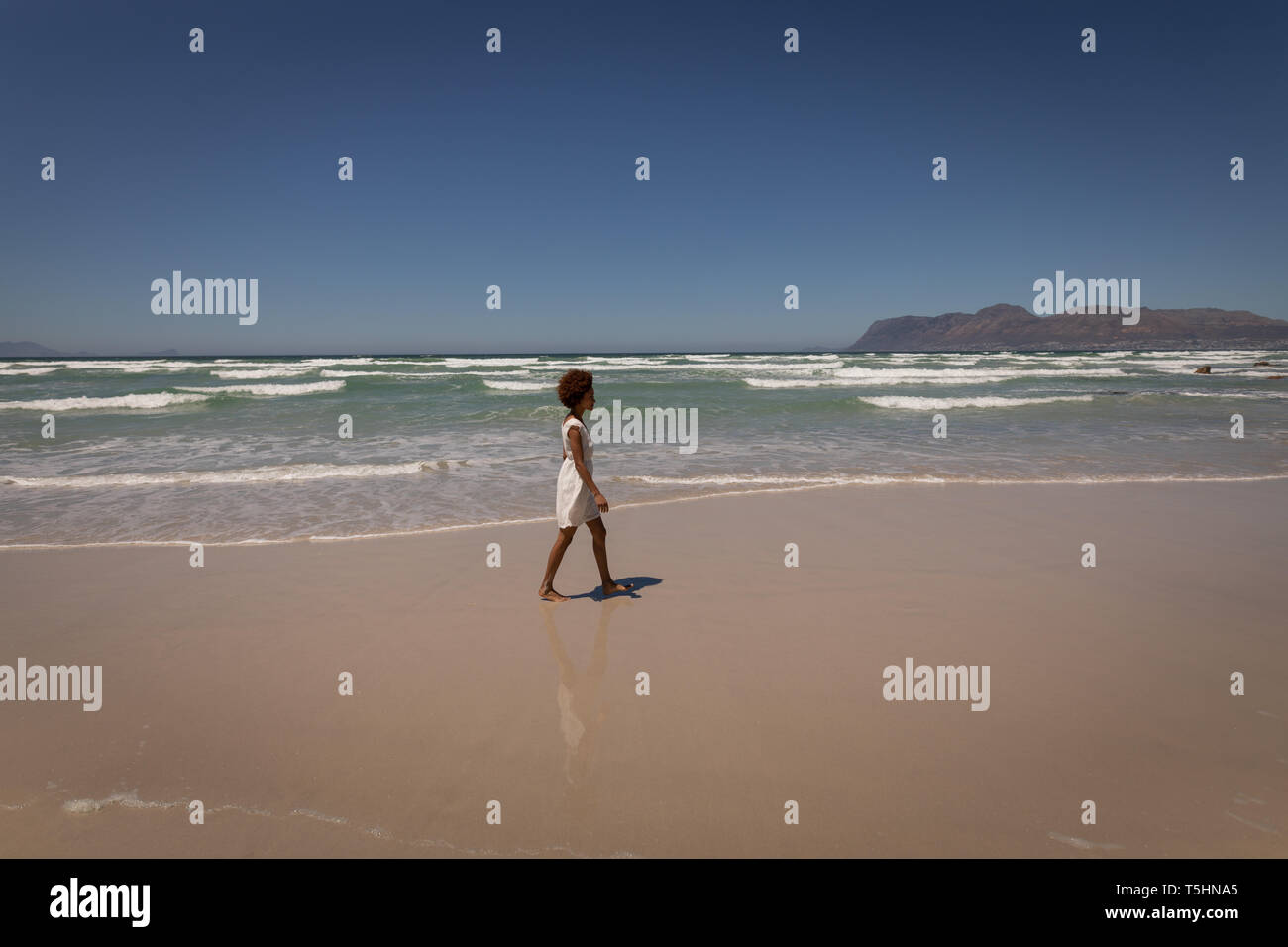 Femme marche seule à la plage sur une journée ensoleillée Banque D'Images Femme marche seule à la plage sur une journée ensoleillée Banque D'Images