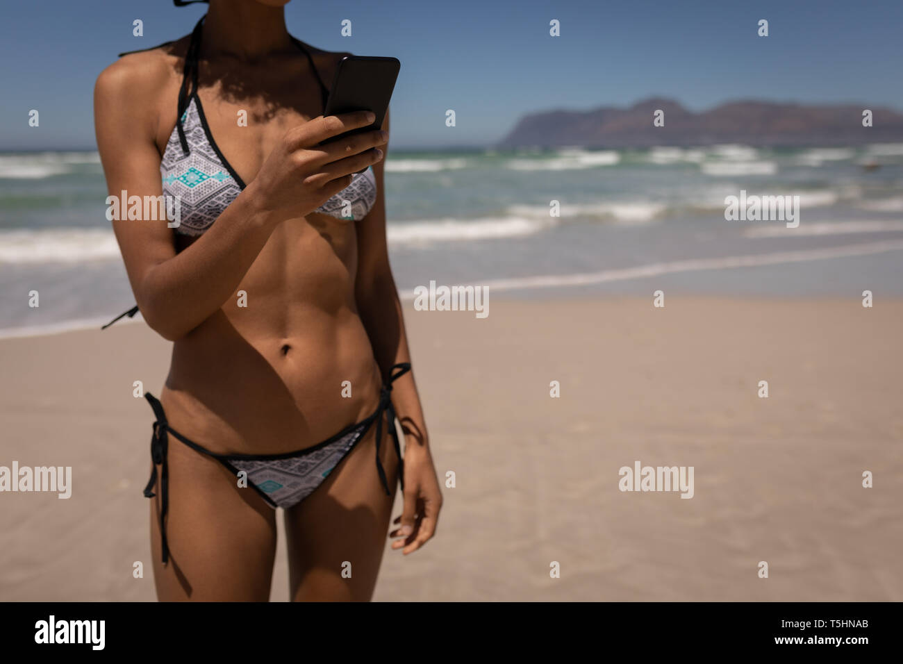 Woman in bikini à l'aide de téléphone mobile sur la plage Banque D'Images Woman in bikini à l'aide de téléphone mobile sur la plage Banque D'Images