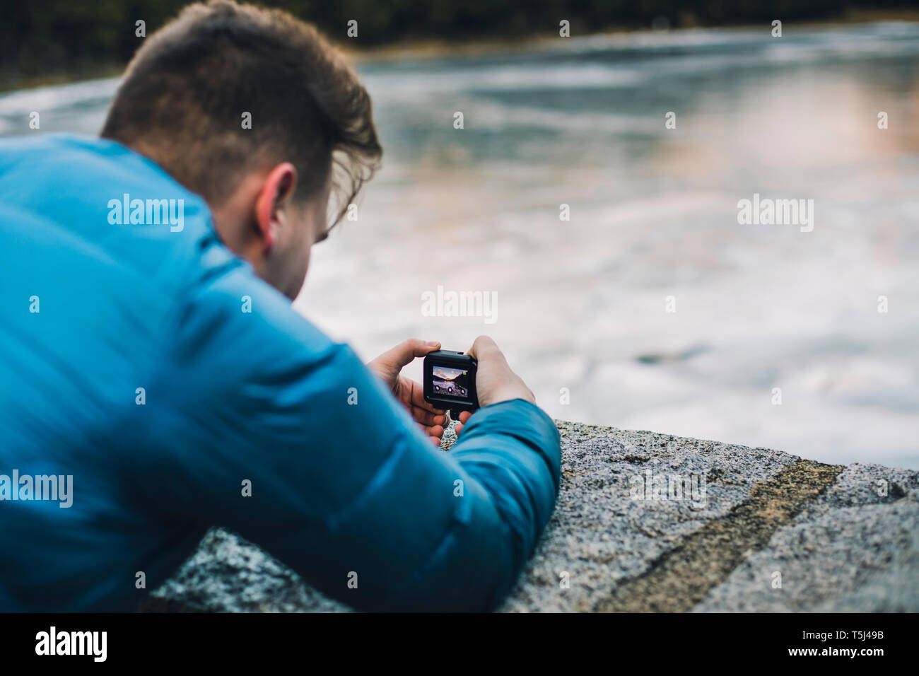 Jeune homme à prendre des photos d'un lac gelé avec une petite caméra Banque D'Images