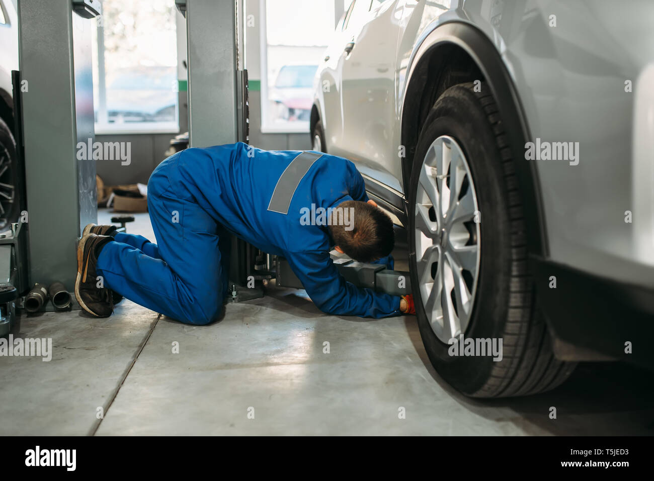 Réparateur à cric de levage uniforme ajuste en voiture, service de diagnostic de la suspension. Service de l'automobile, de l'entretien des véhicules Banque D'Images Réparateur à cric de levage uniforme ajuste en voiture, service de diagnostic de la suspension. Service de l'automobile, de l'entretien des véhicules Banque D'Images