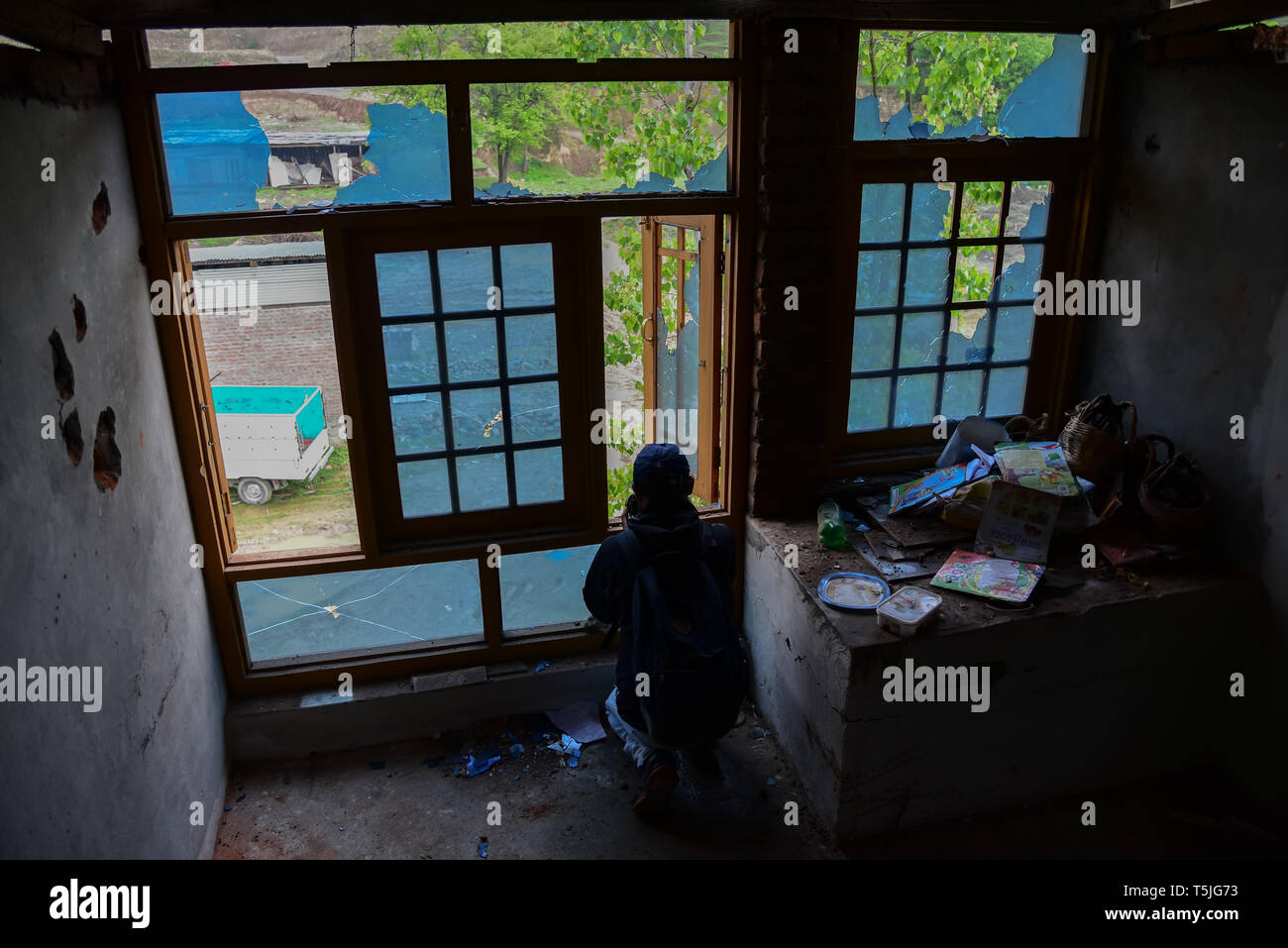 Un photojournaliste vu près de la fenêtres d'une maison endommagée en partie après une fusillade entre des militants et les forces du gouvernement indien dans Bijbehara. Dans une fusillade avant l'aube le jeudi, deux militants ont été tués par les forces du Gouvernement indien dans Anantang Bijbehara au sud de Srinagar, Cachemire sous administration indienne, a annoncé la police. Banque D'Images