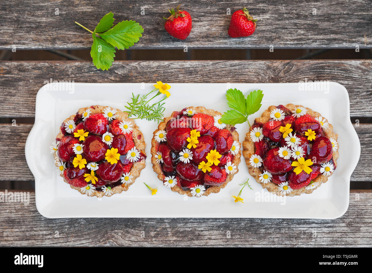 Tartelettes aux fraises maison coeur avec Daisy et fleurs de souci d'or, fleurs comestibles, en bois Banque D'Images