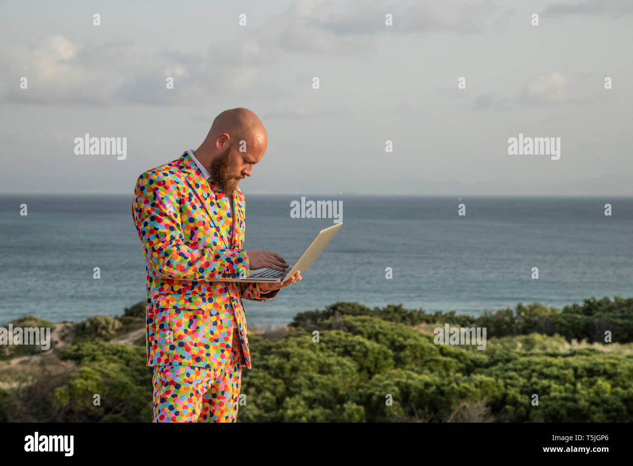 Homme portant un costume avec colorful polka-dots using laptop Banque D'Images