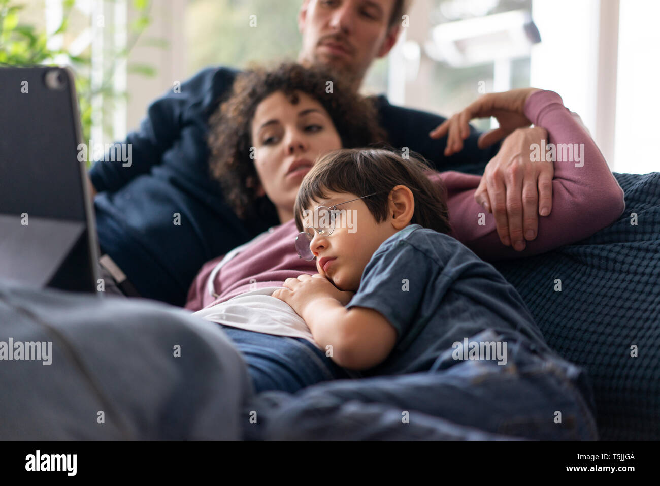 Family lying on couch watching movie sur theit tablet Banque D'Images