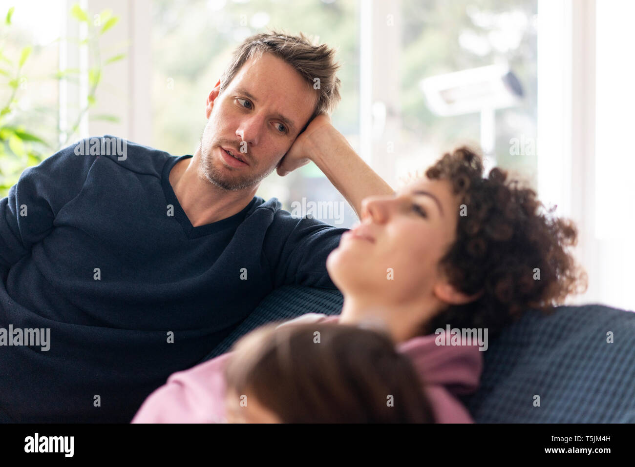 Homme qui regarde sa femme se détendre sur le canapé Banque D'Images